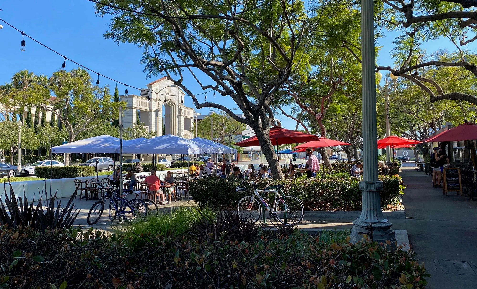 People enjoy an outdoor dining area partially blocking a main boulevard in downtown Culver City, Calif.